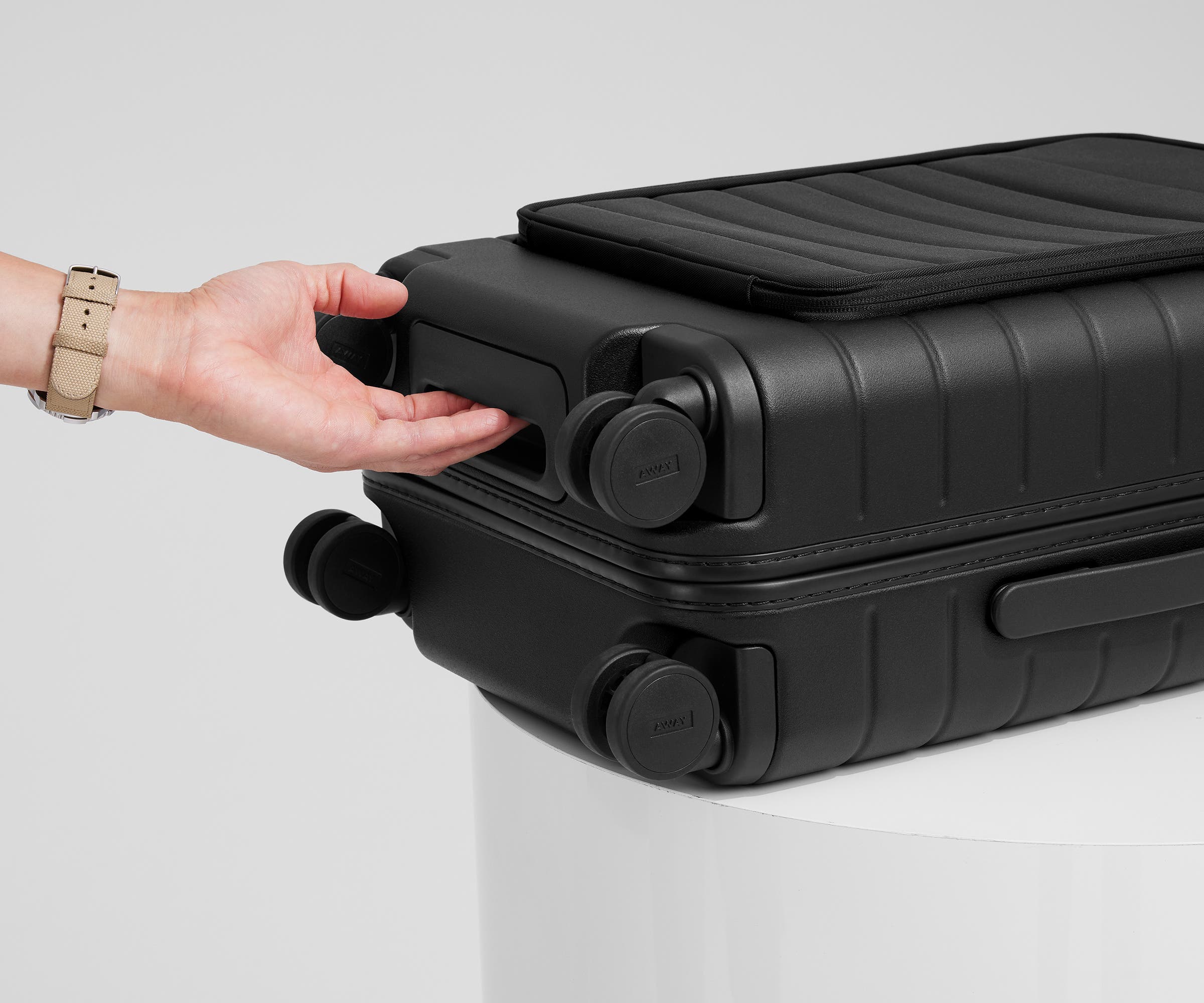 The Front Pocket Carry-On suitcase in Jet Black shown from below highlighting the underside grab handle