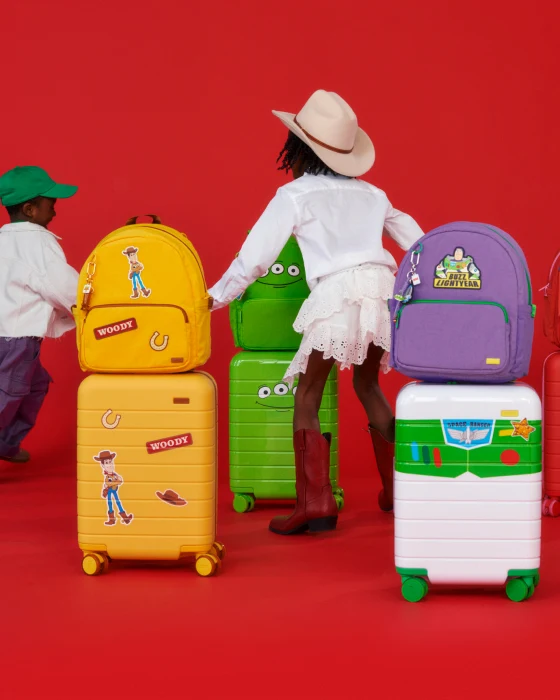 Children playing with colorful suitcases and backpacks on a red background