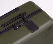 The Large suitcase in Olive Green shown shown from above highlighting TSA-approved combination lock and recycled leather luggage tag