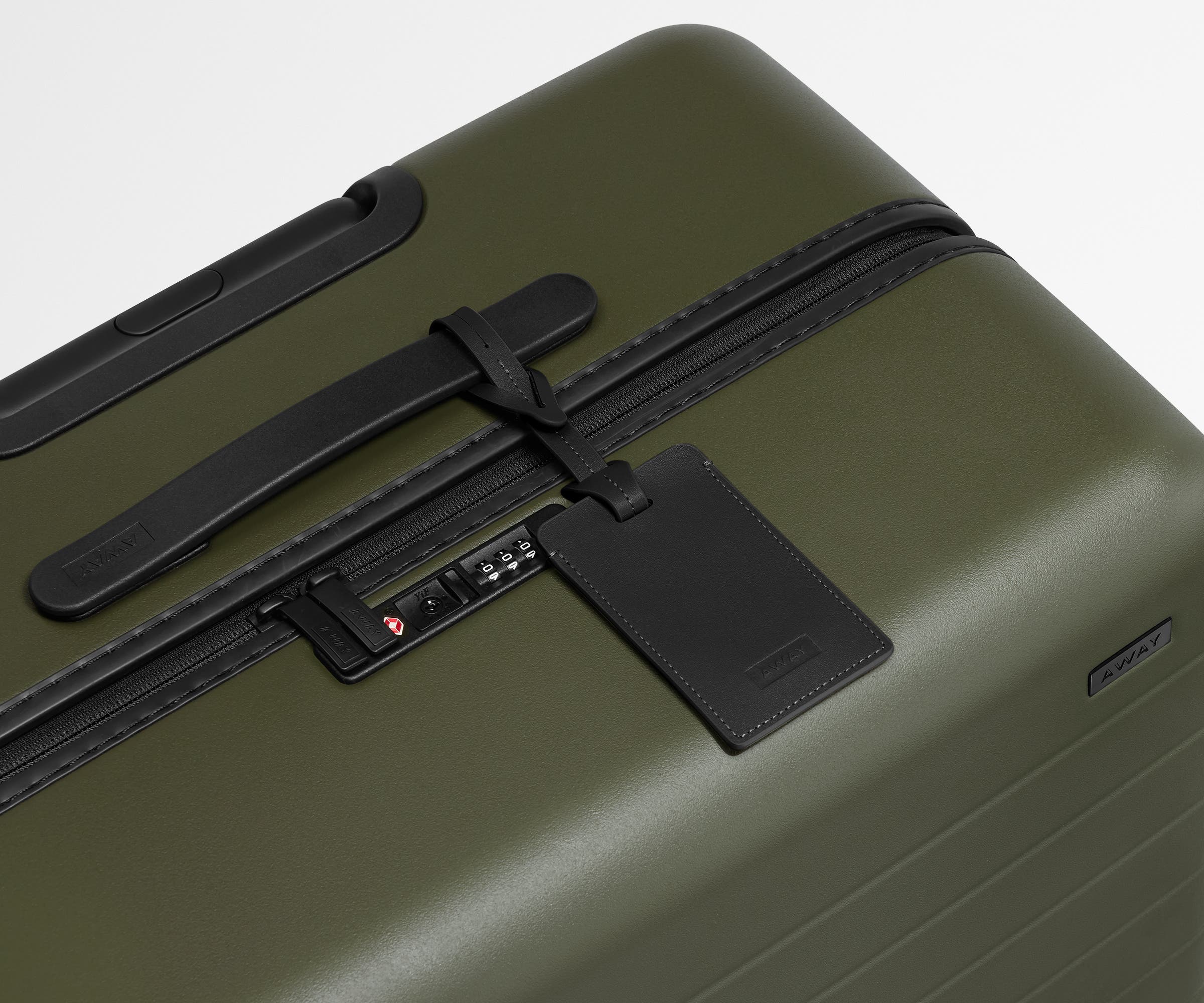 The Large suitcase in Olive Green shown shown from above highlighting TSA-approved combination lock and recycled leather luggage tag