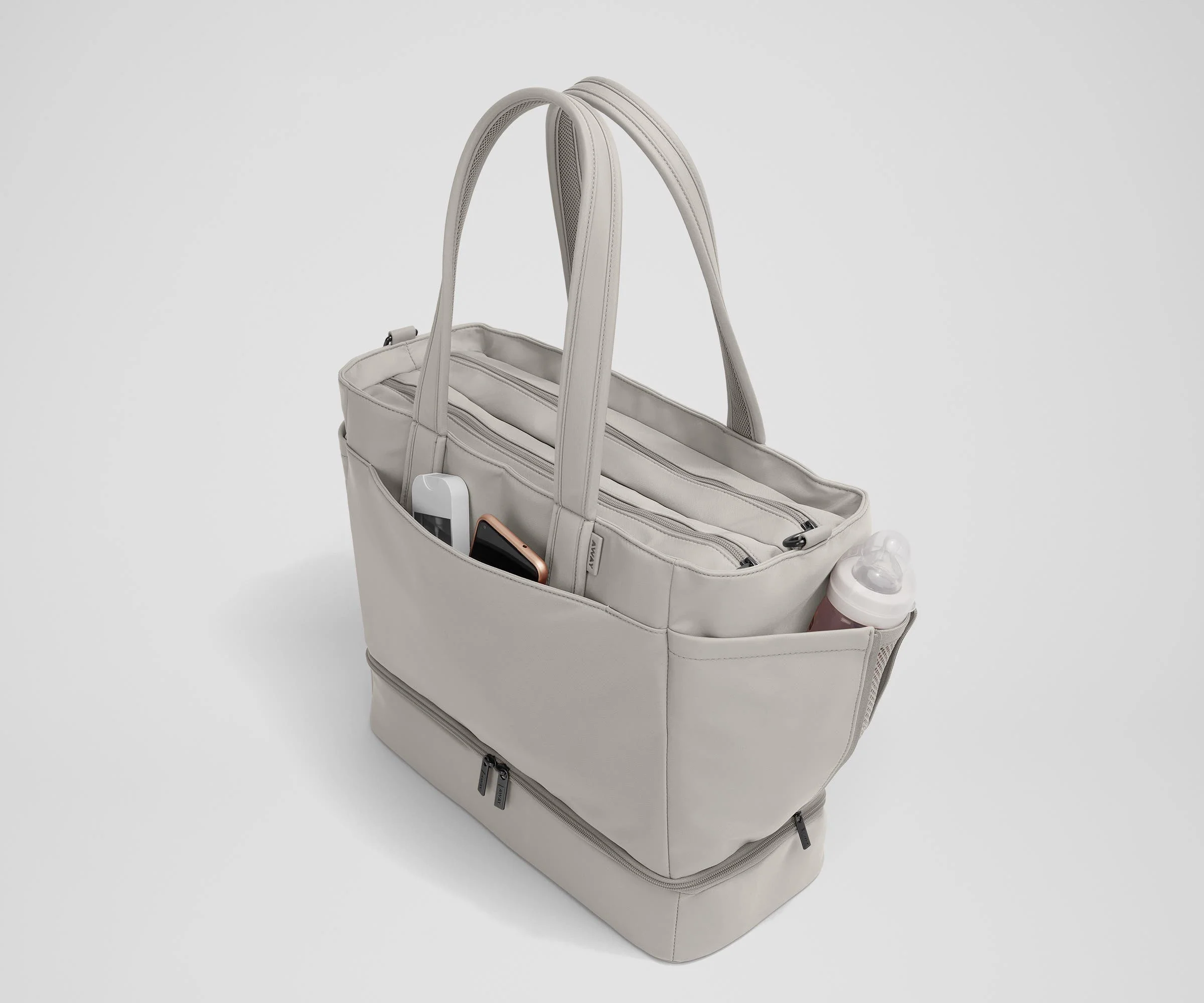 Exterior front pocket packed with hand sanitizer and a phone. Exterior bottle pocket packed with a milk bottle