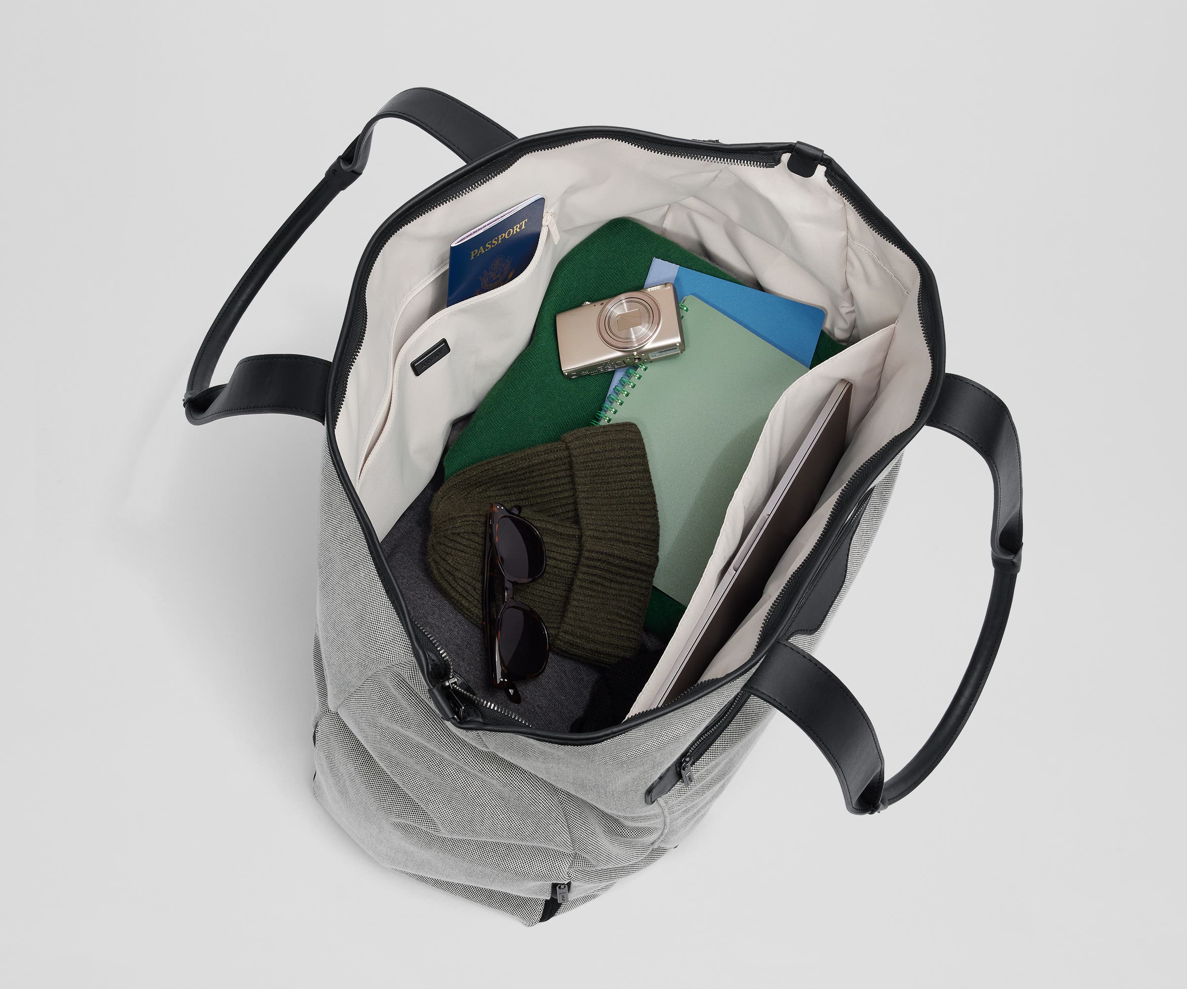 Top-down view of the tote packed with clothing, passport, headphones, a notebook, and a laptop among other travel essentials
