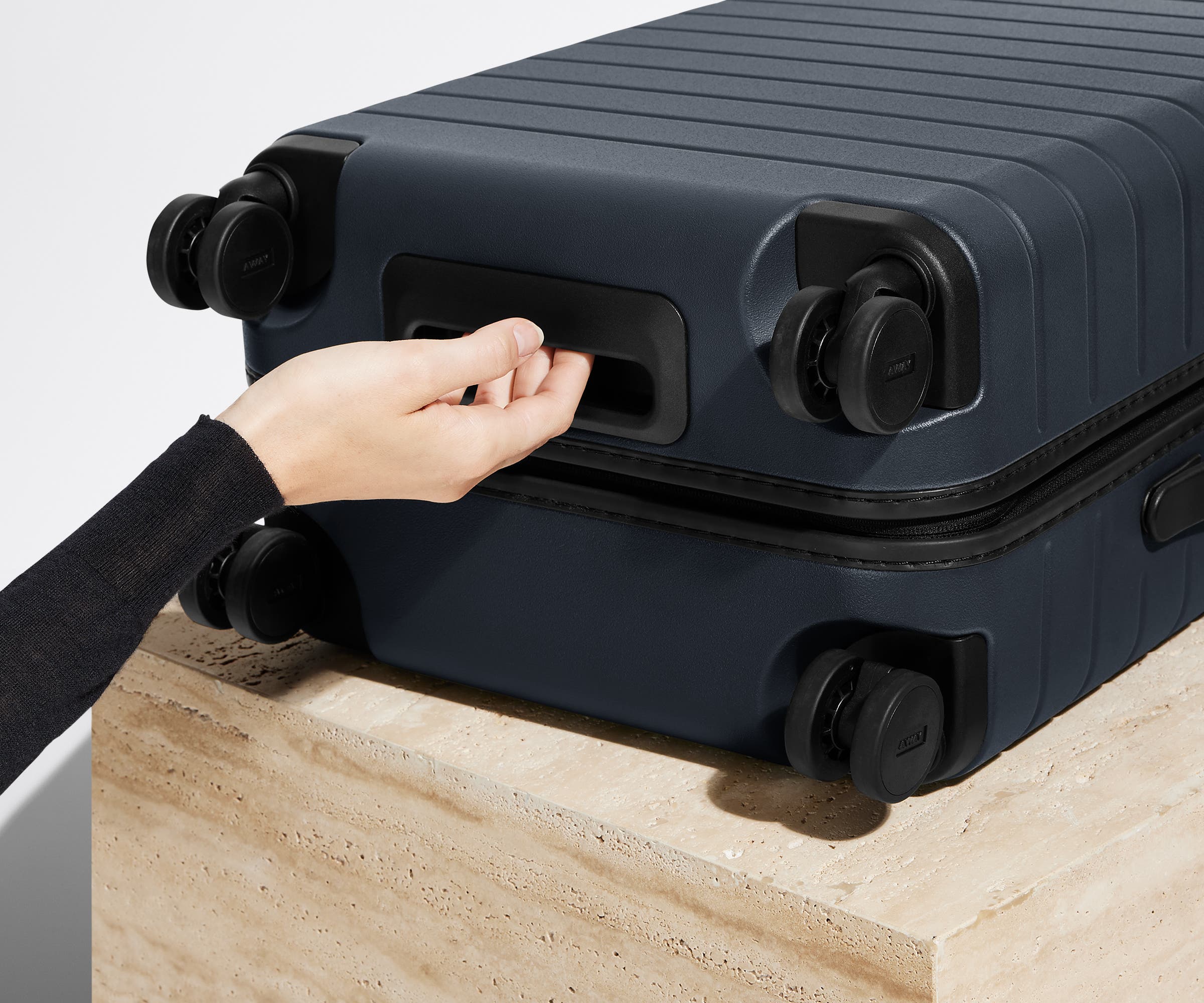The Carry-On suitcase in Navy Blue shown from below highlighting the underside grab handle