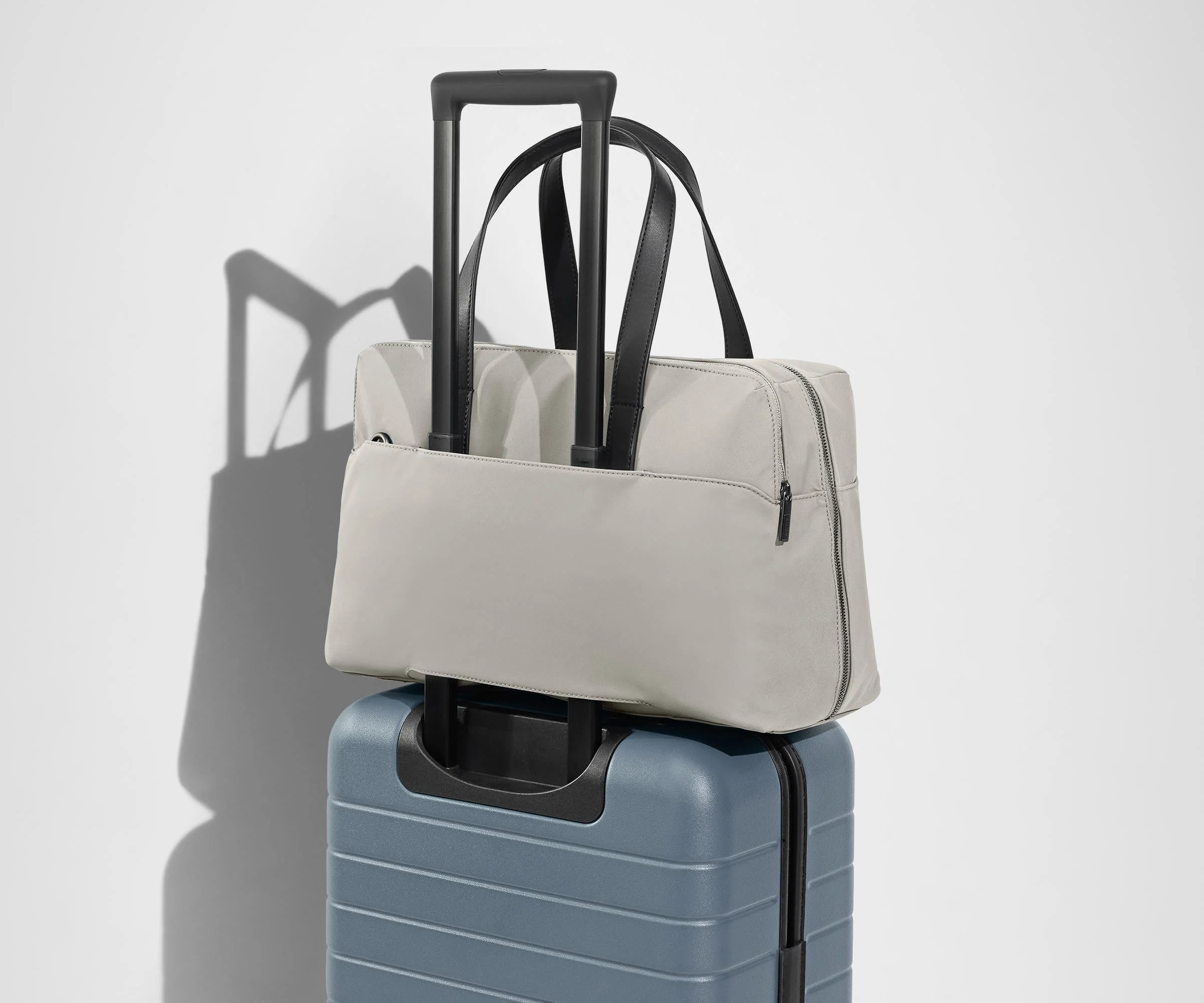 The Everywhere Bag secured to an Away suitcase by its trolley sleeve