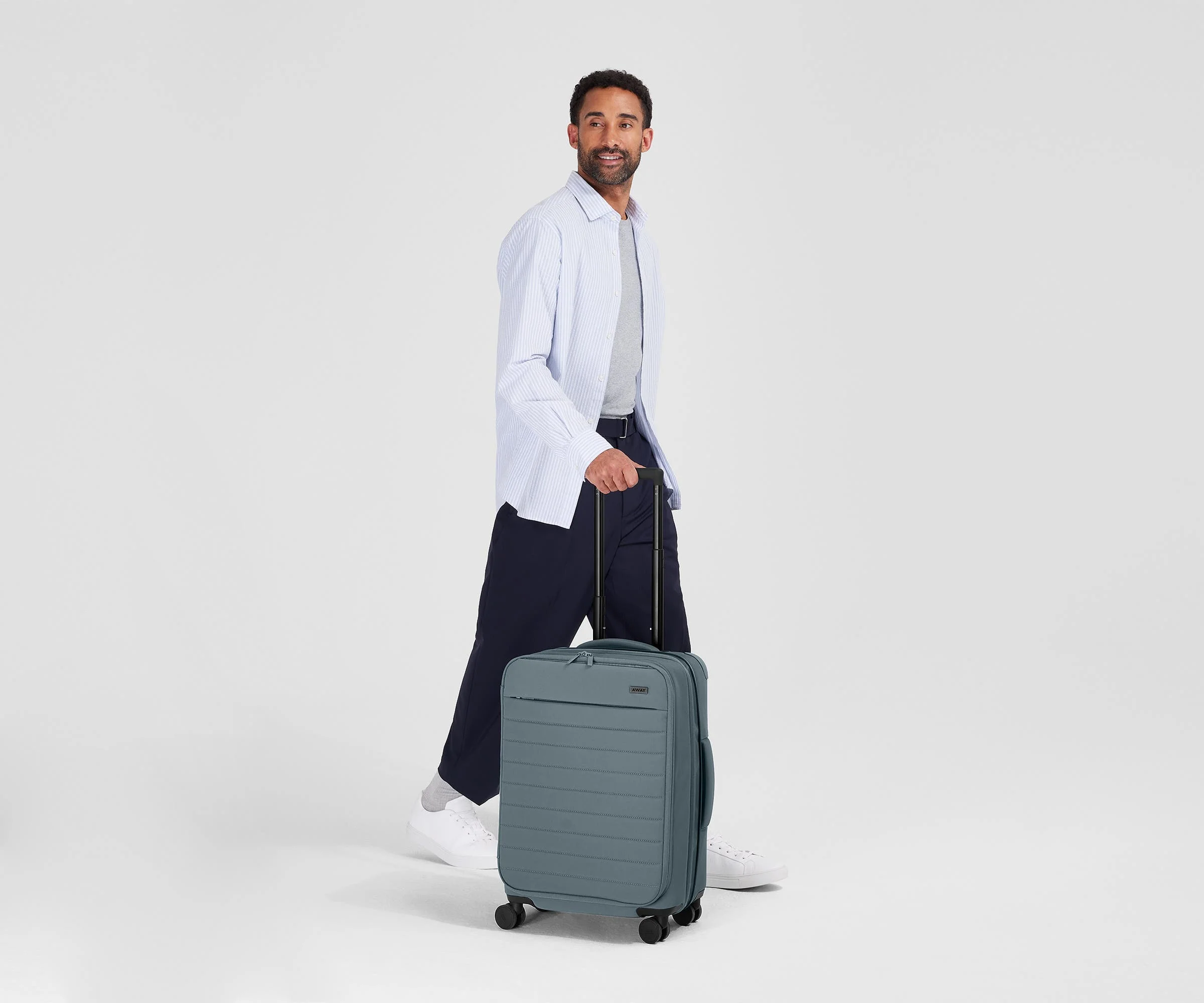 Person standing next to the Softside Bigger Carry-on for scale