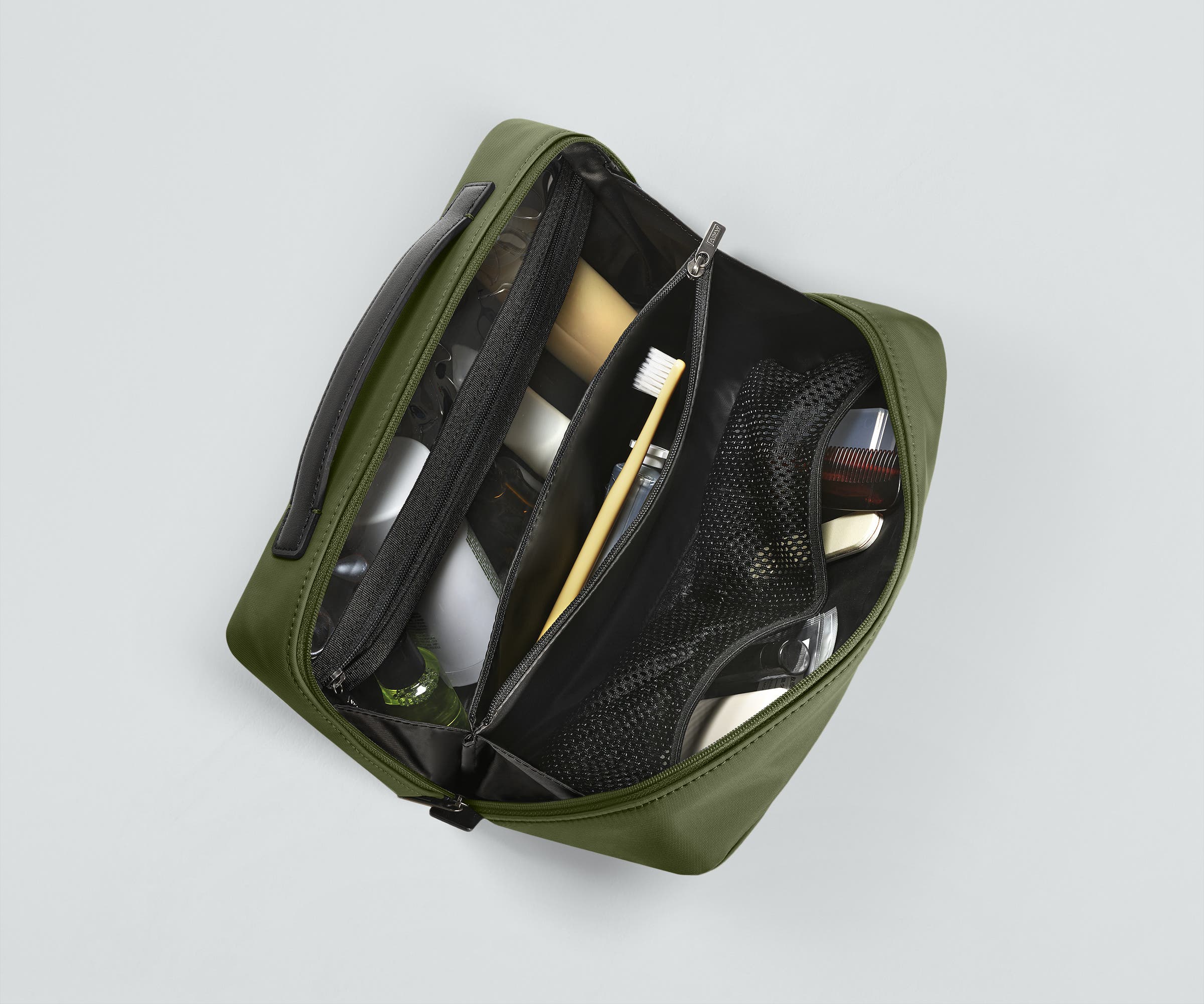 Clear zip pocket packed with travel-sized toiletries. Center zip compartment packed with a toothbrush and toothpaste. The Mesh pockets packed with nail care and other toiletries