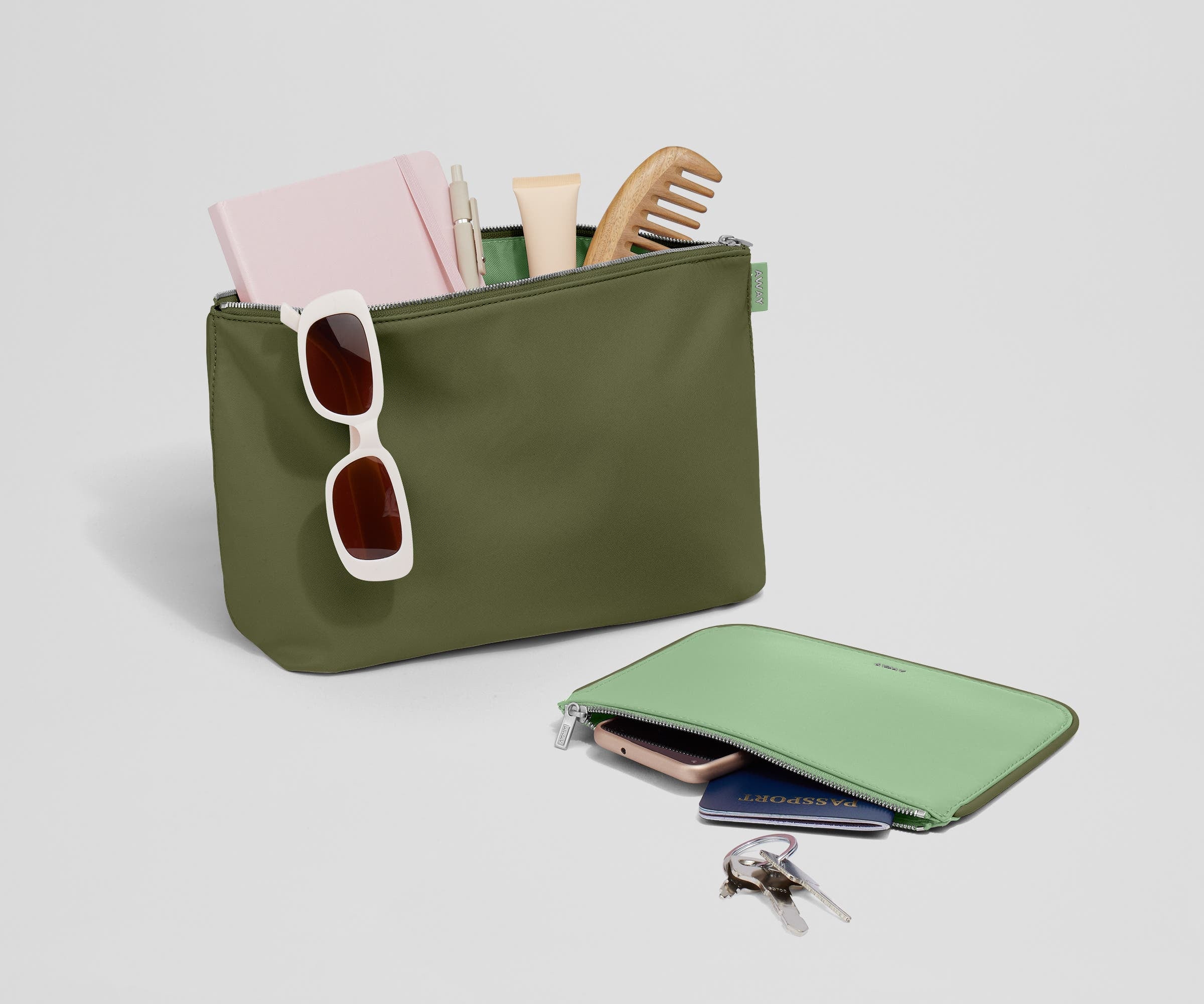 Pouch duo packed with travel essentials like a notebook, passport, keys, and sunglasses