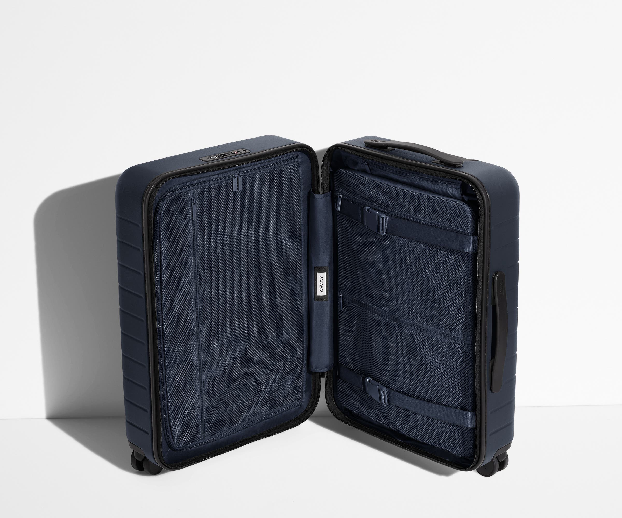 The Carry-On suitcase in Navy Blue shown open in an upright position to show interior organization and compression system