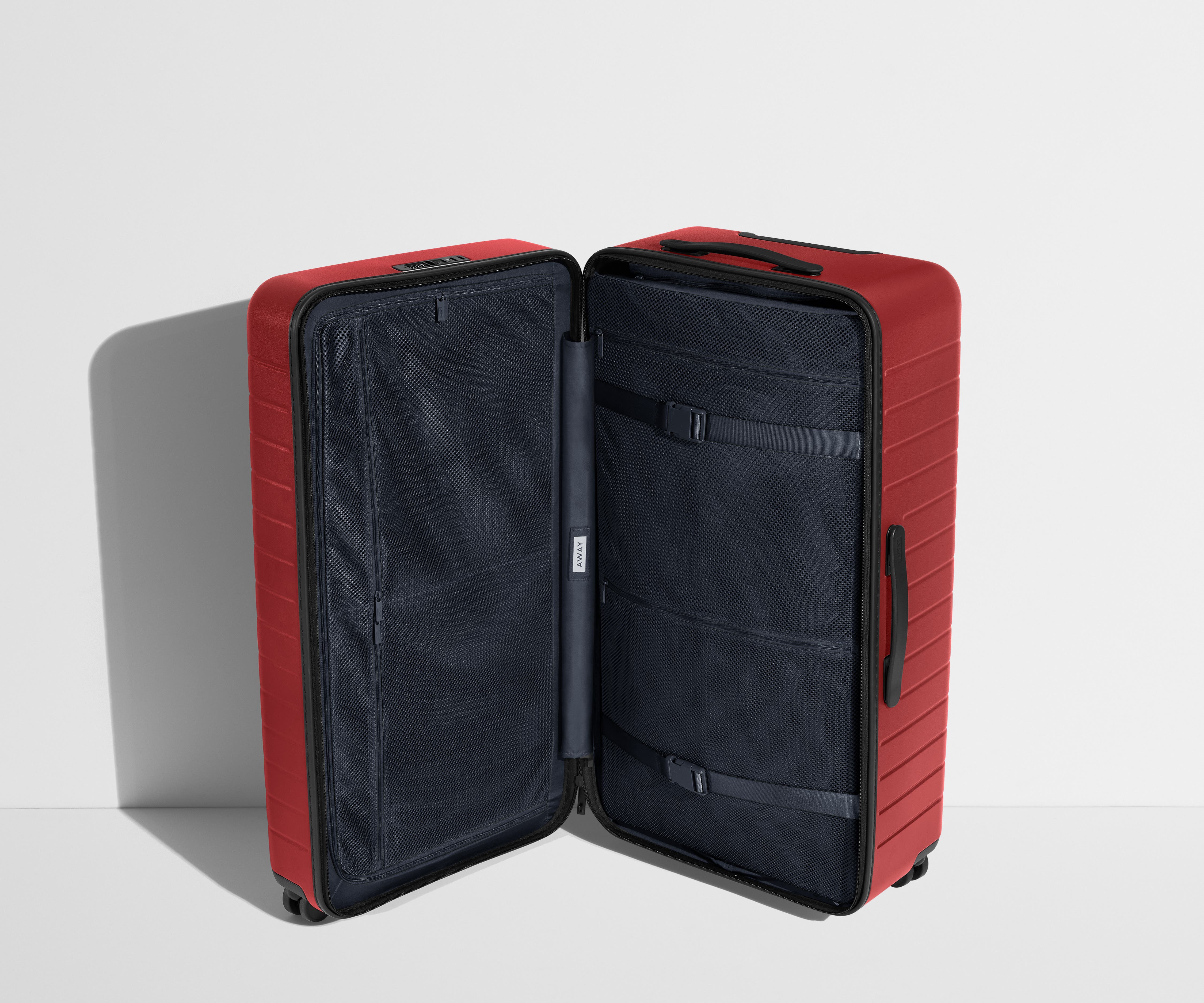 The Trunk suitcase in Tango Red shown open in an upright position to show interior organization and compression system