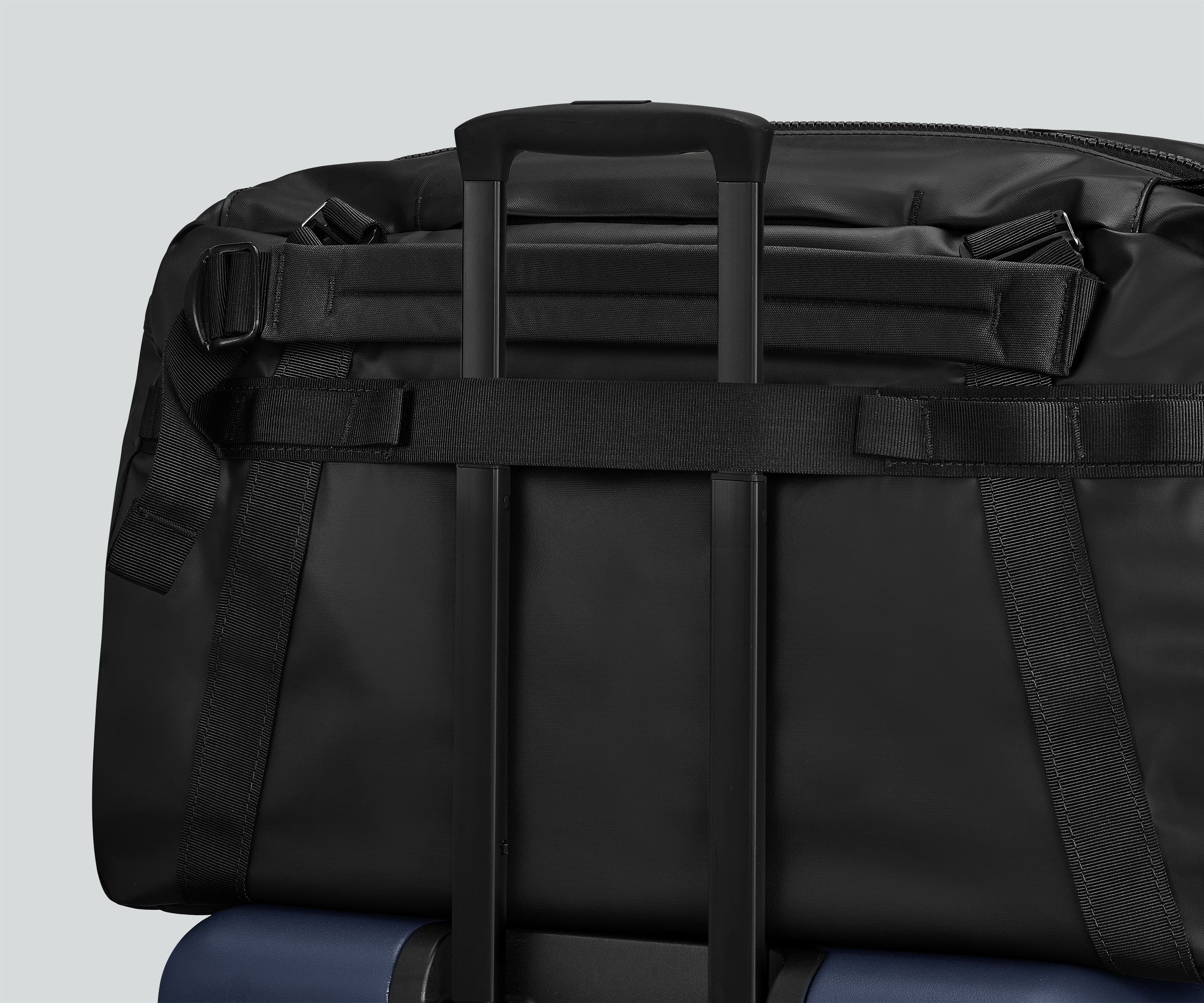 55L duffle bag secured to an Away suitcase by the trolley sleeve