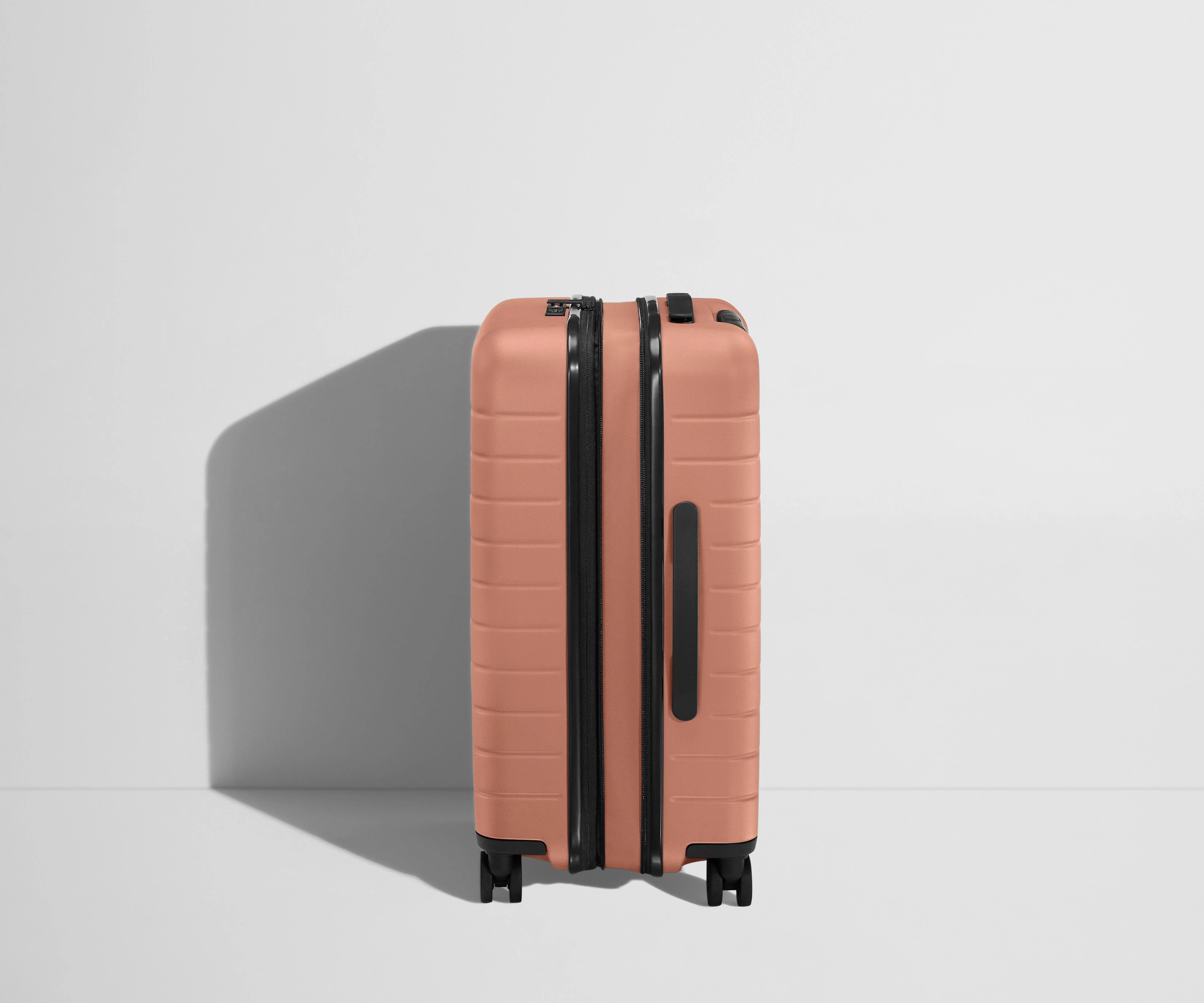 Side product view of The Bigger Carry-On Flex suitcase in Clay Pink shown fully expanded