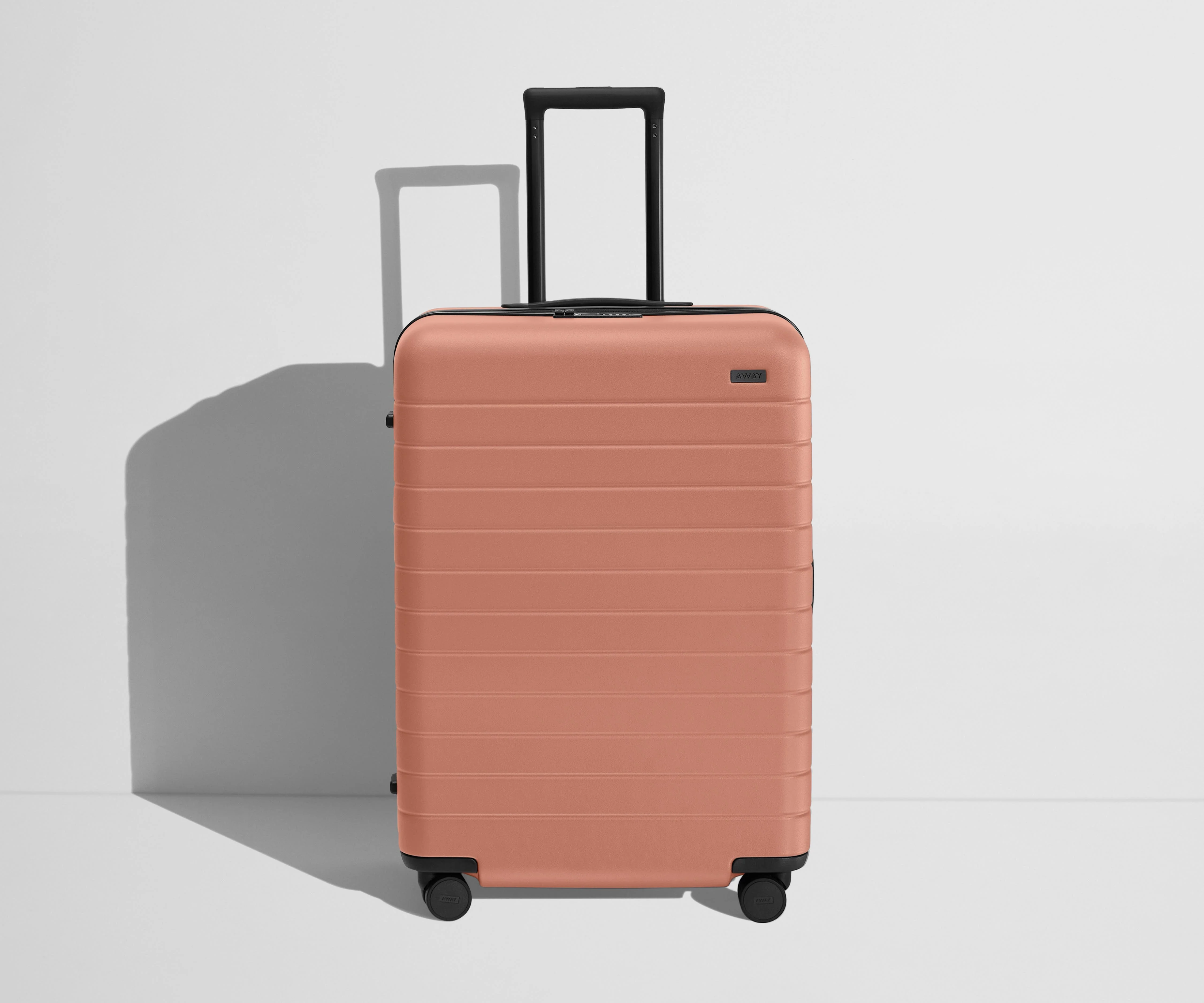 Front product view of The Medium Flex suitcase in Clay Pink with raised handle