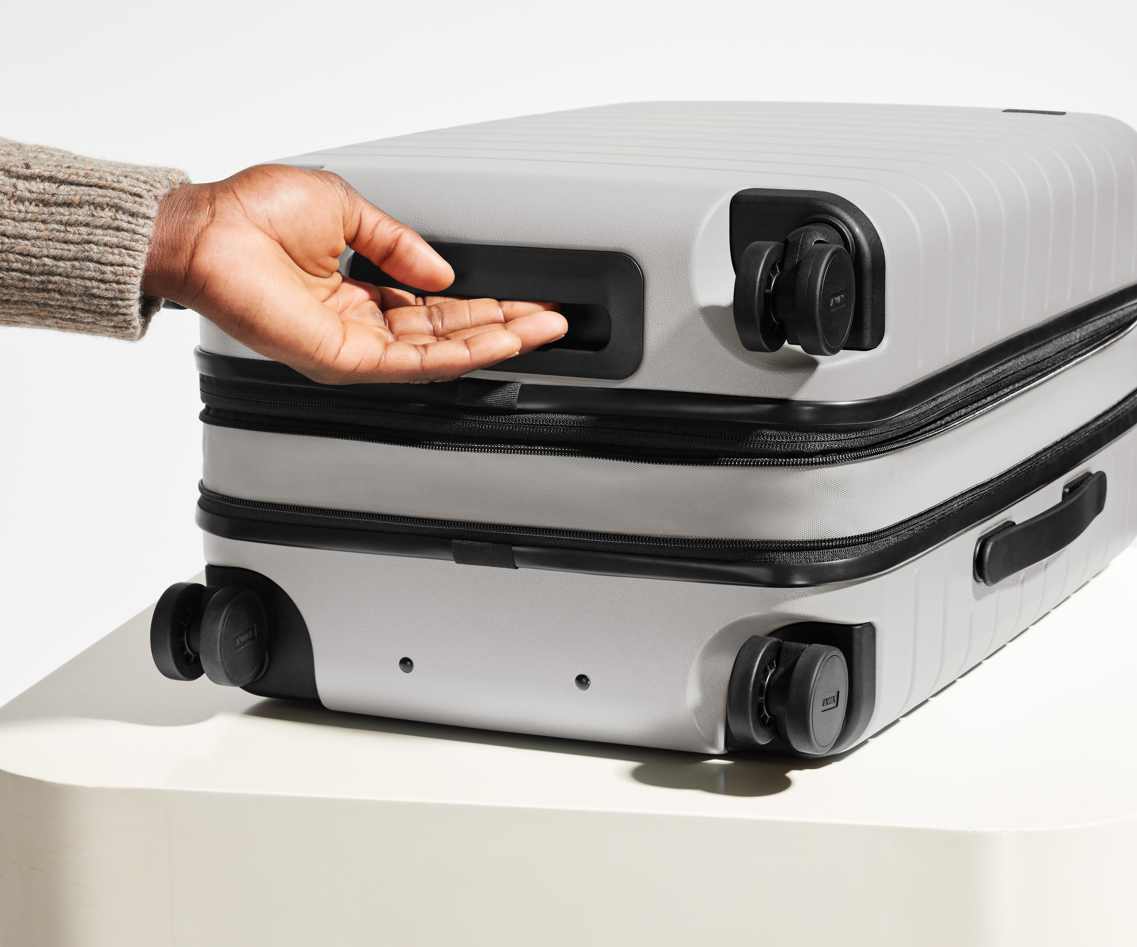 The Carry-On Flex suitcase in Cloud Gray shown from below highlighting the underside grab handle