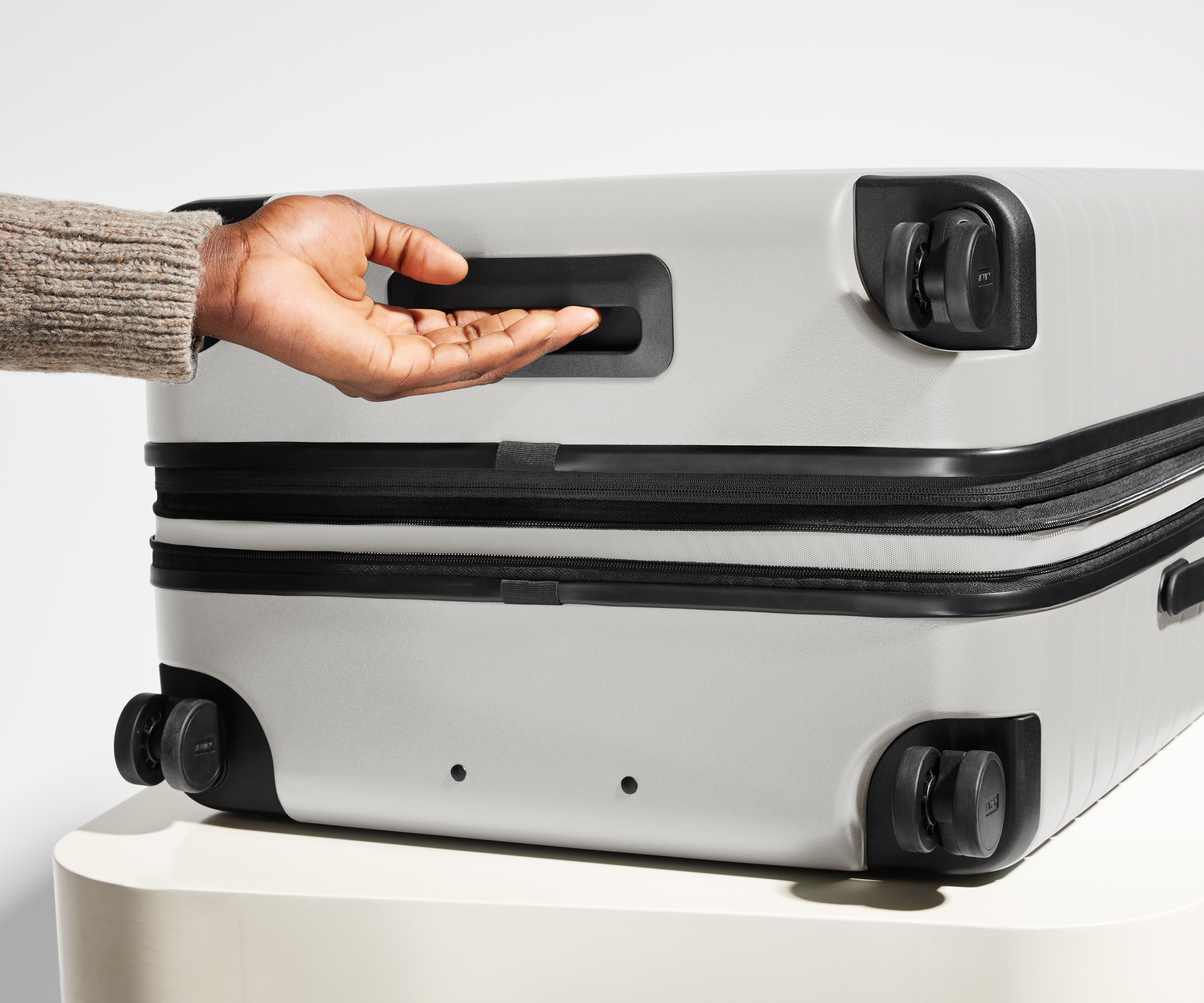 The Medium Flex suitcase in Cloud Gray shown from below highlighting the underside grab handle