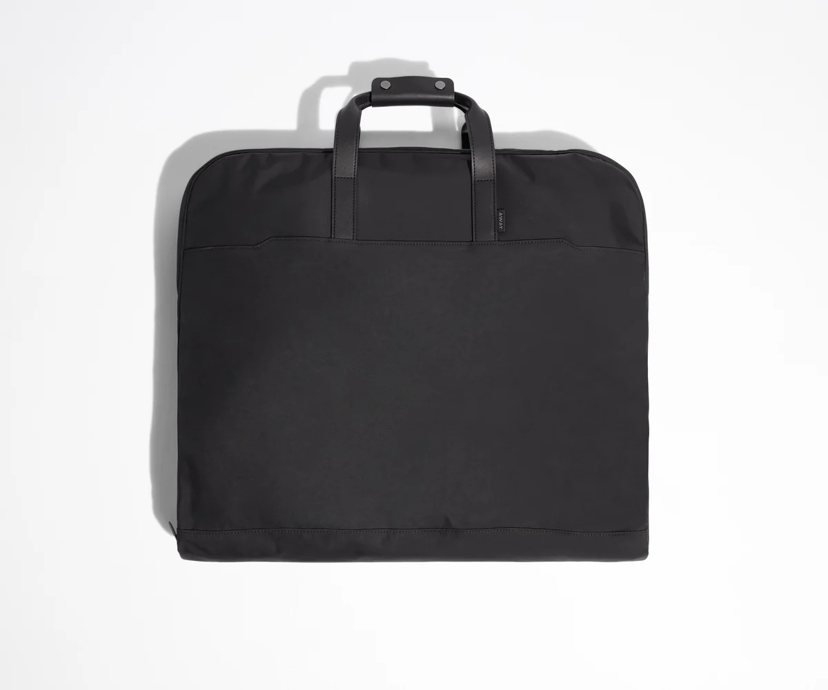 Black garment bag folded view with leather trim handles.