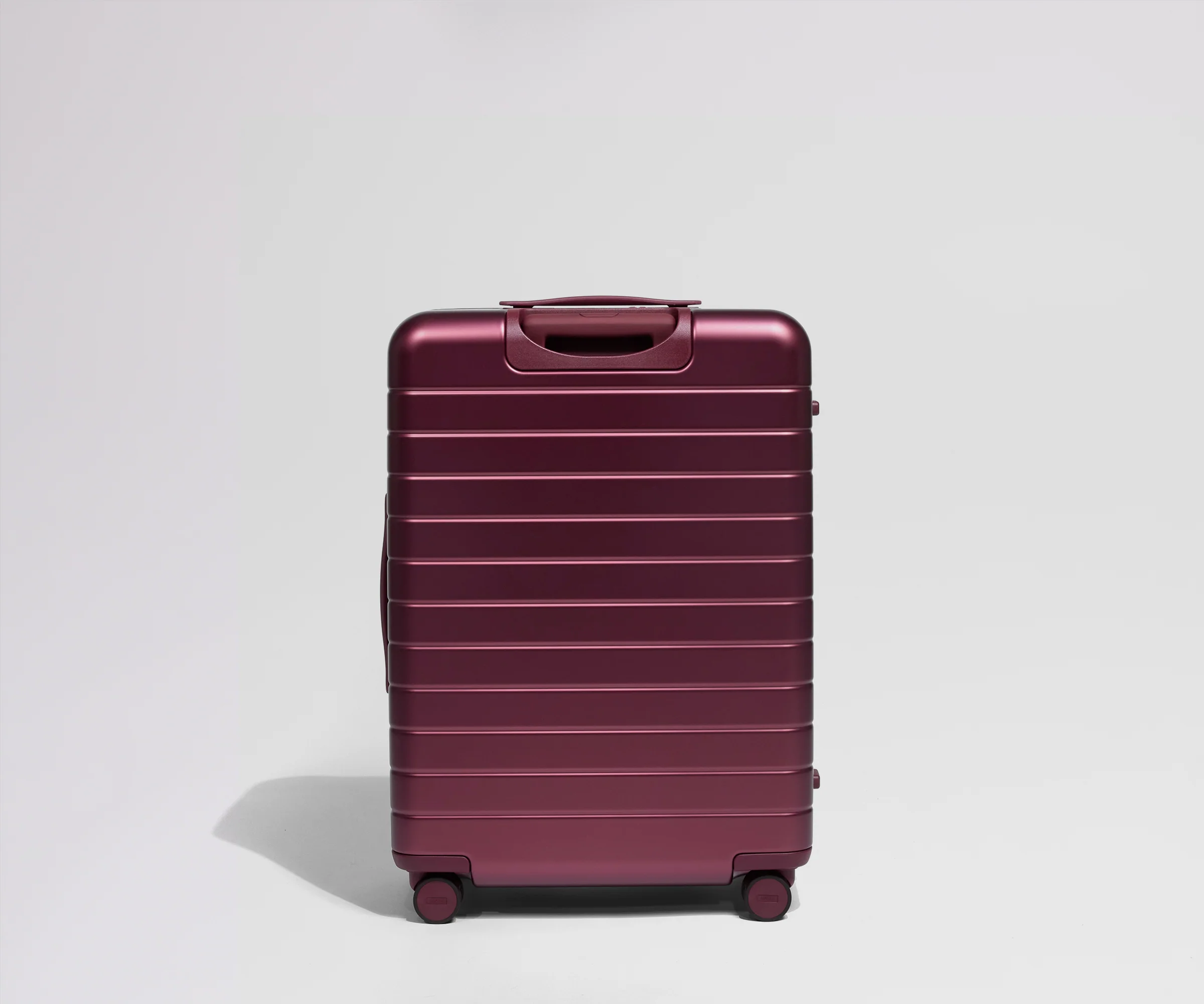 Back view of a maroon suitcase on a light gray background