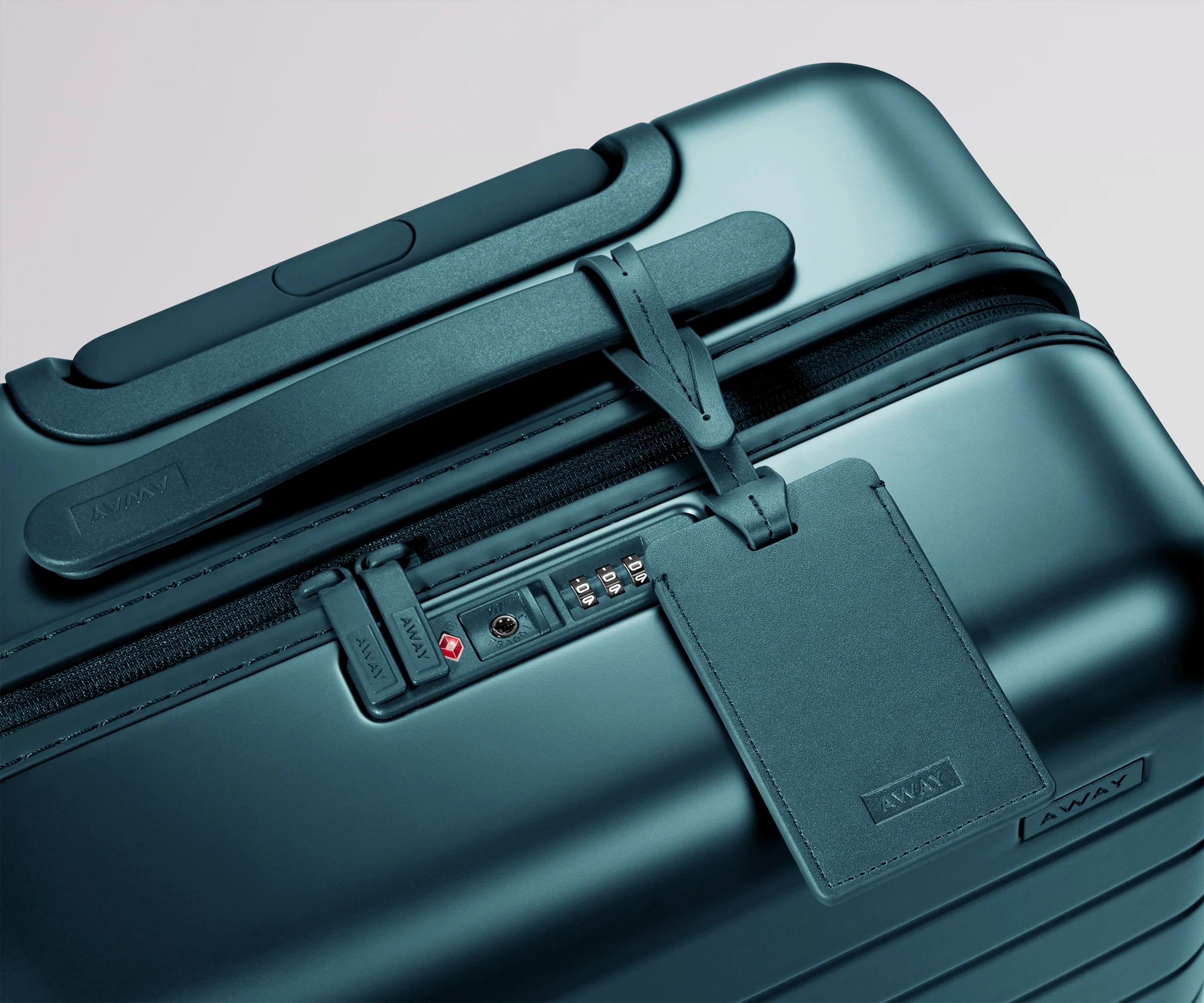 Teal suitcase with a matching leather luggage tag