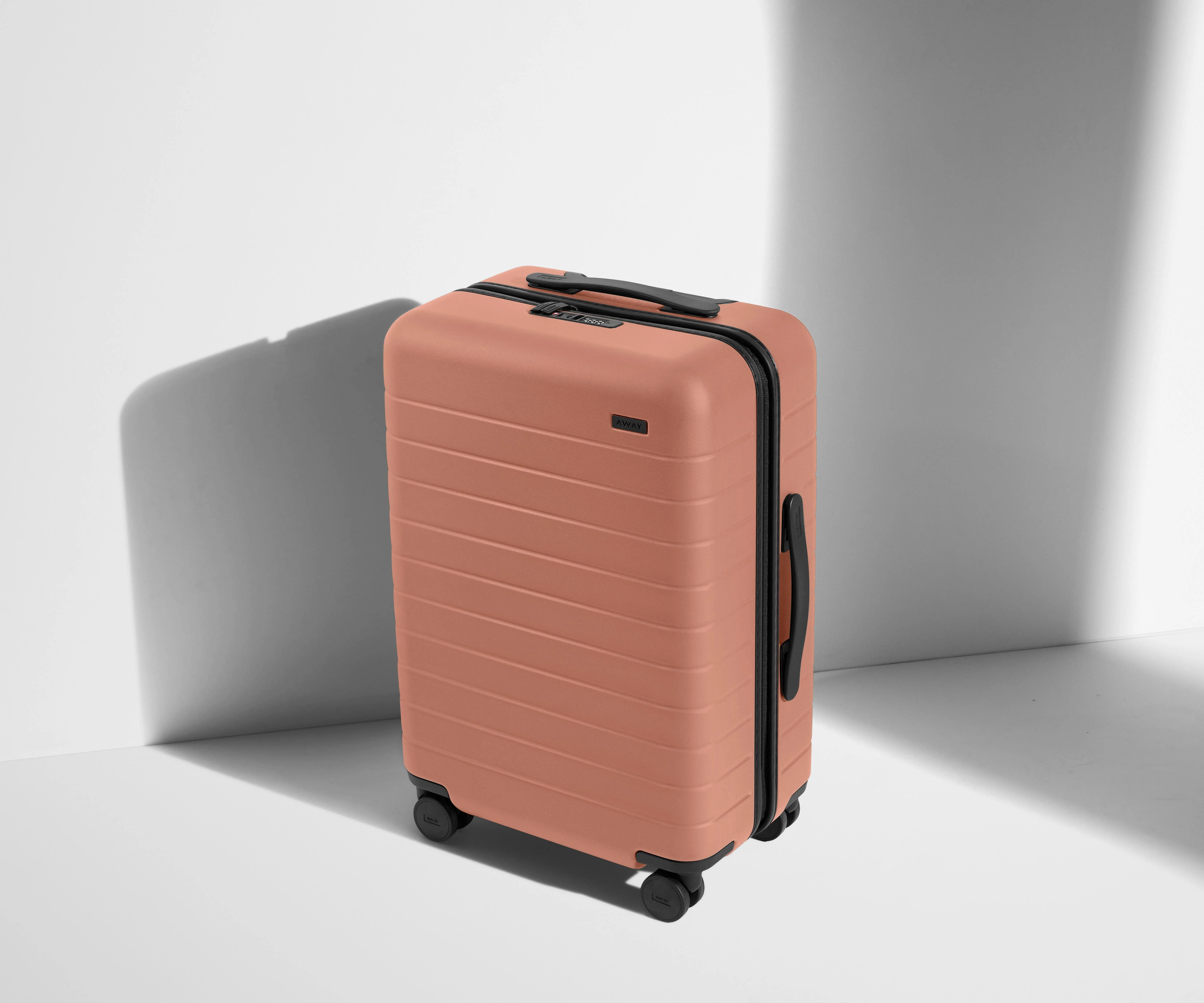 Angled product view of The Bigger Carry-On suitcase in Clay Pink