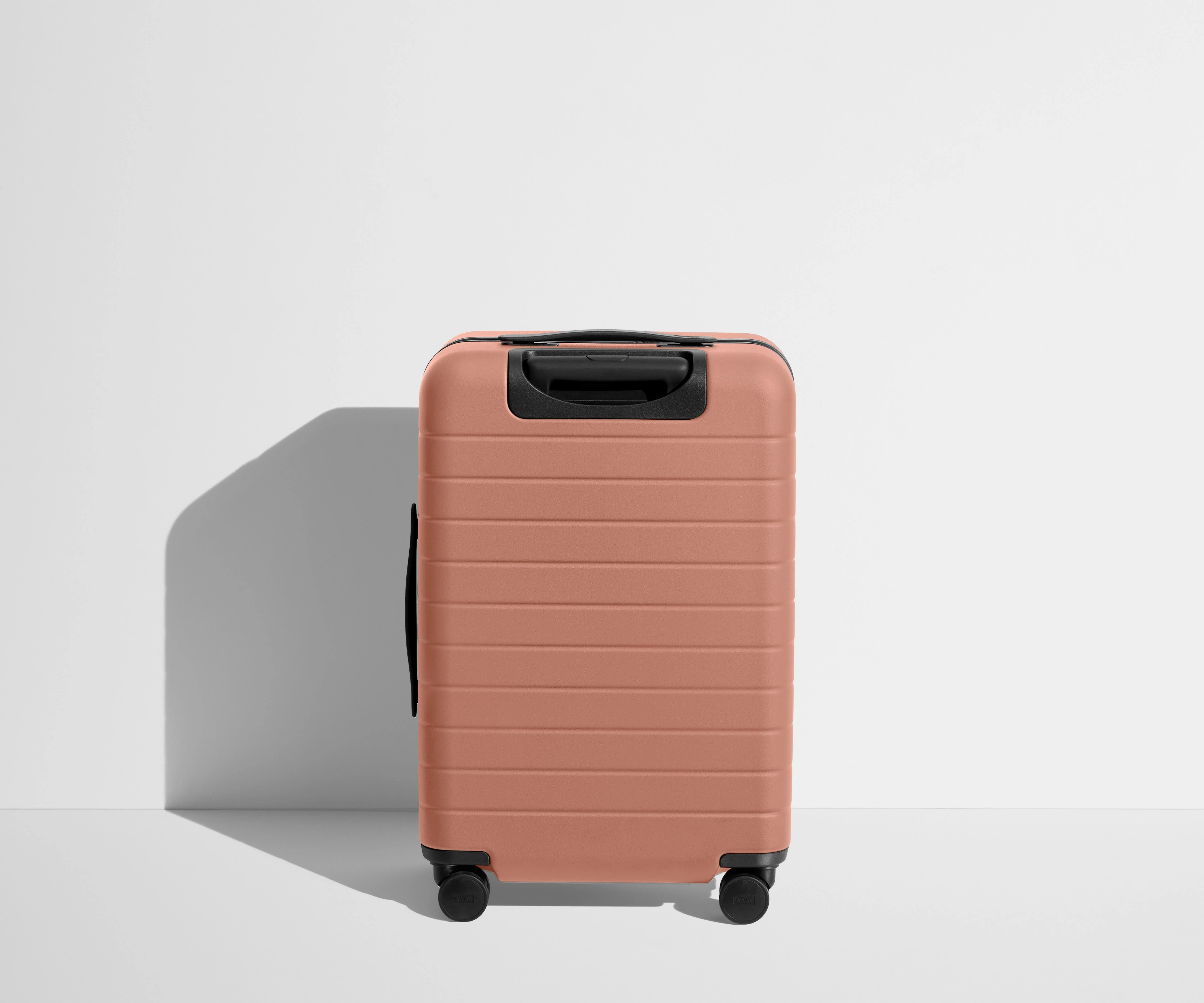 Back product view of The Bigger Carry-On suitcase in Clay Pink