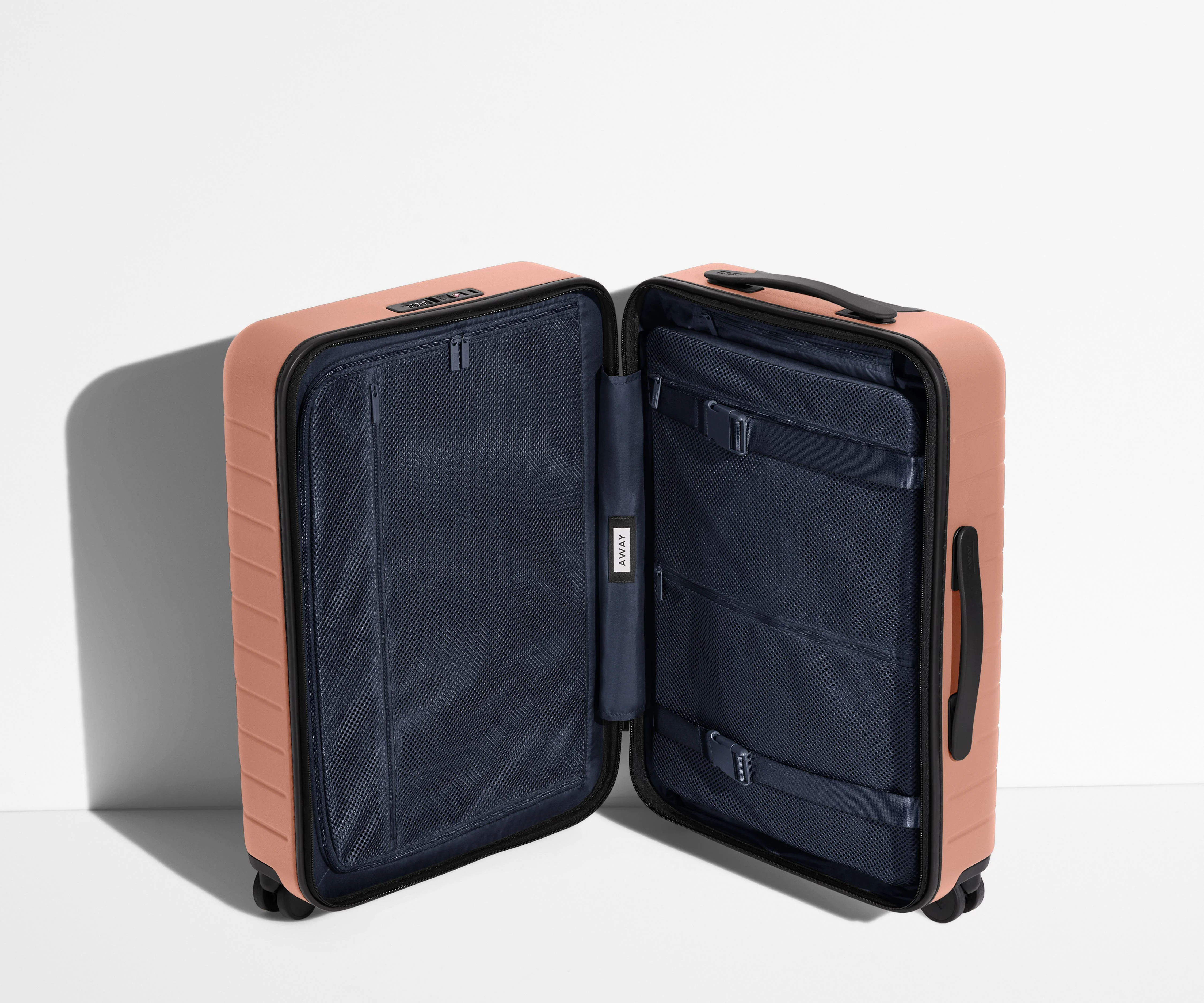 The Carry-On suitcase in Clay Pink shown open in an upright position to show interior organization and compression system