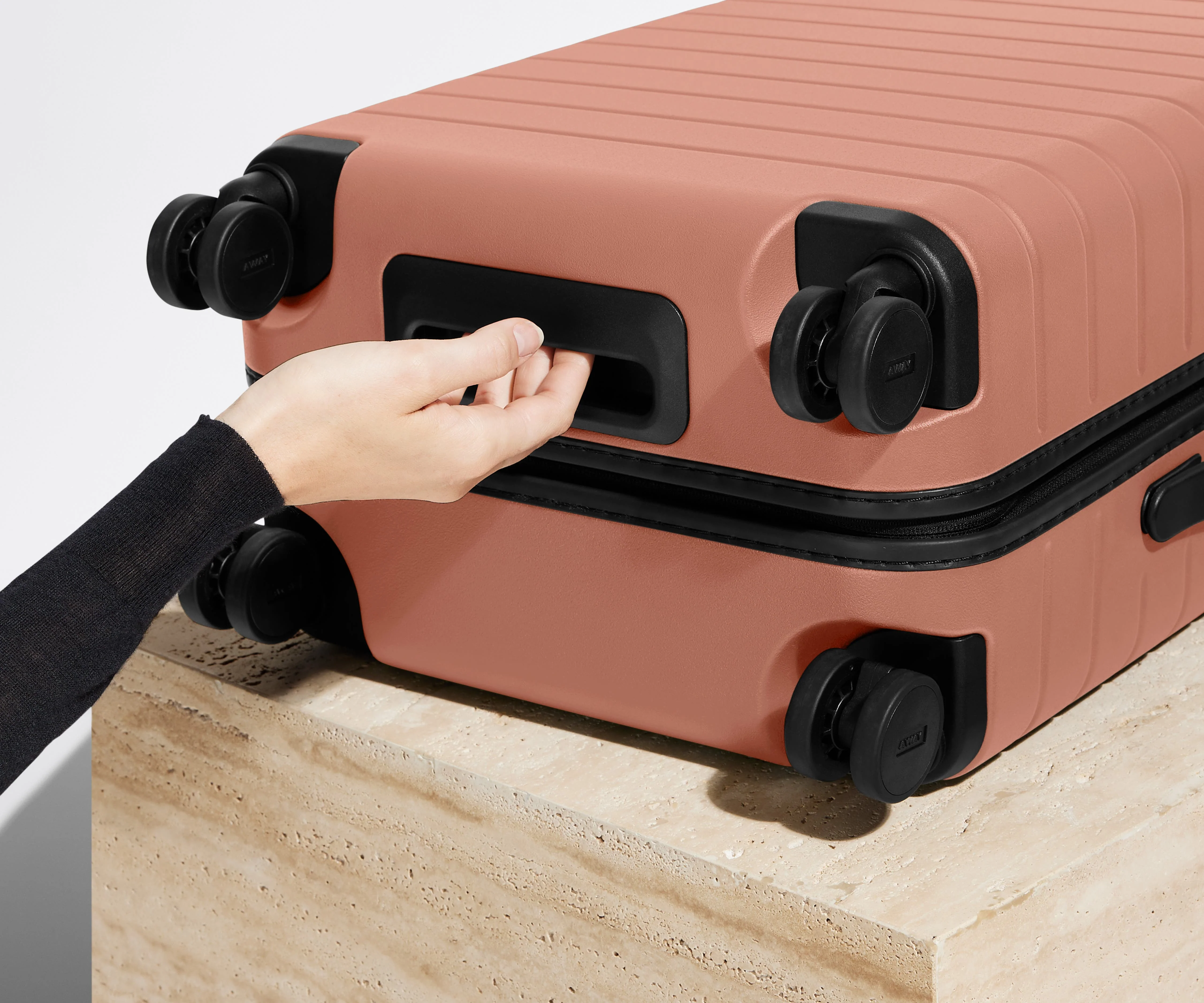 The Carry-On suitcase in Clay Pink shown from below highlighting the underside grab handle