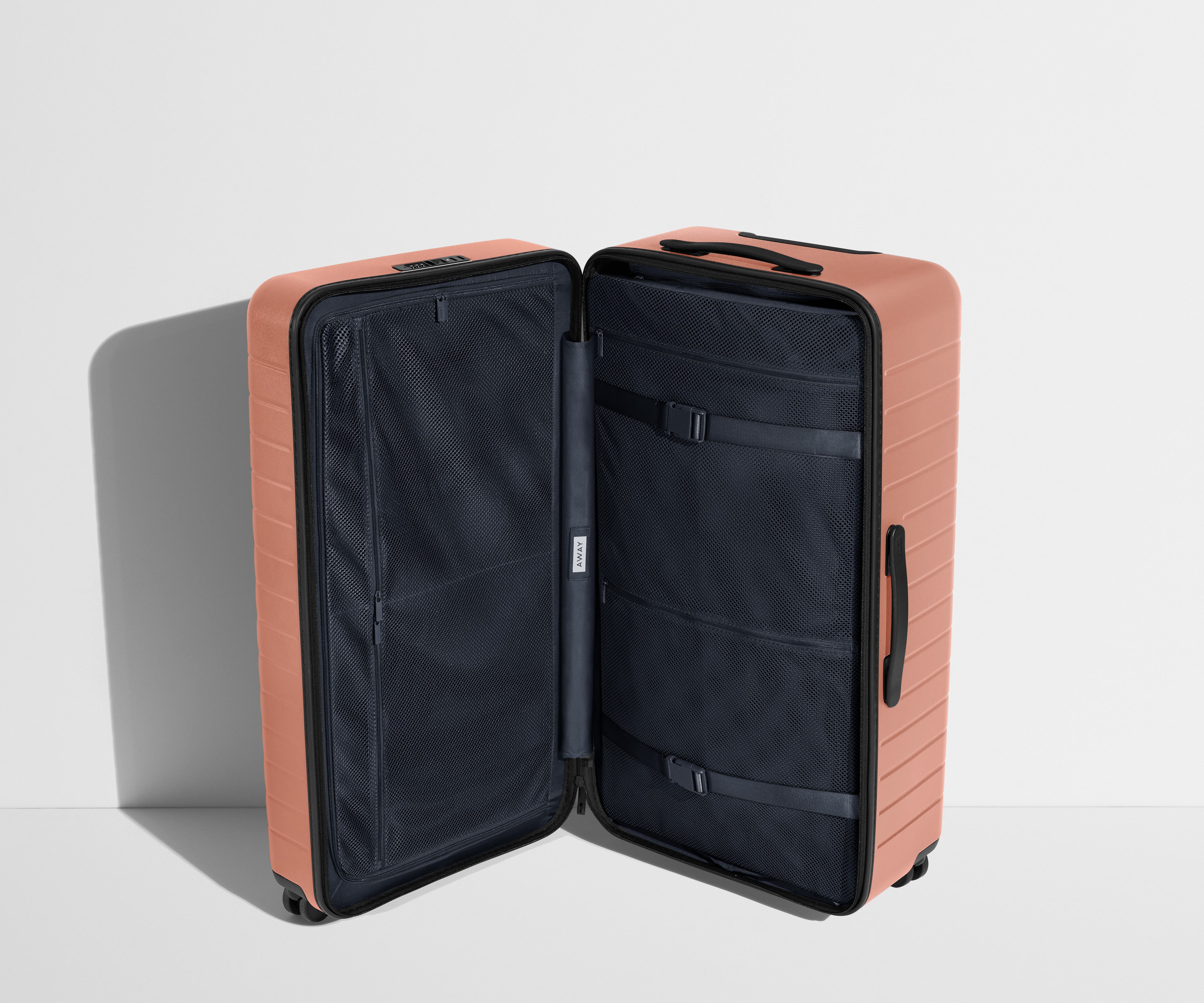 The Trunk suitcase in Clay Pink shown open in an upright position to show interior organization and compression system
