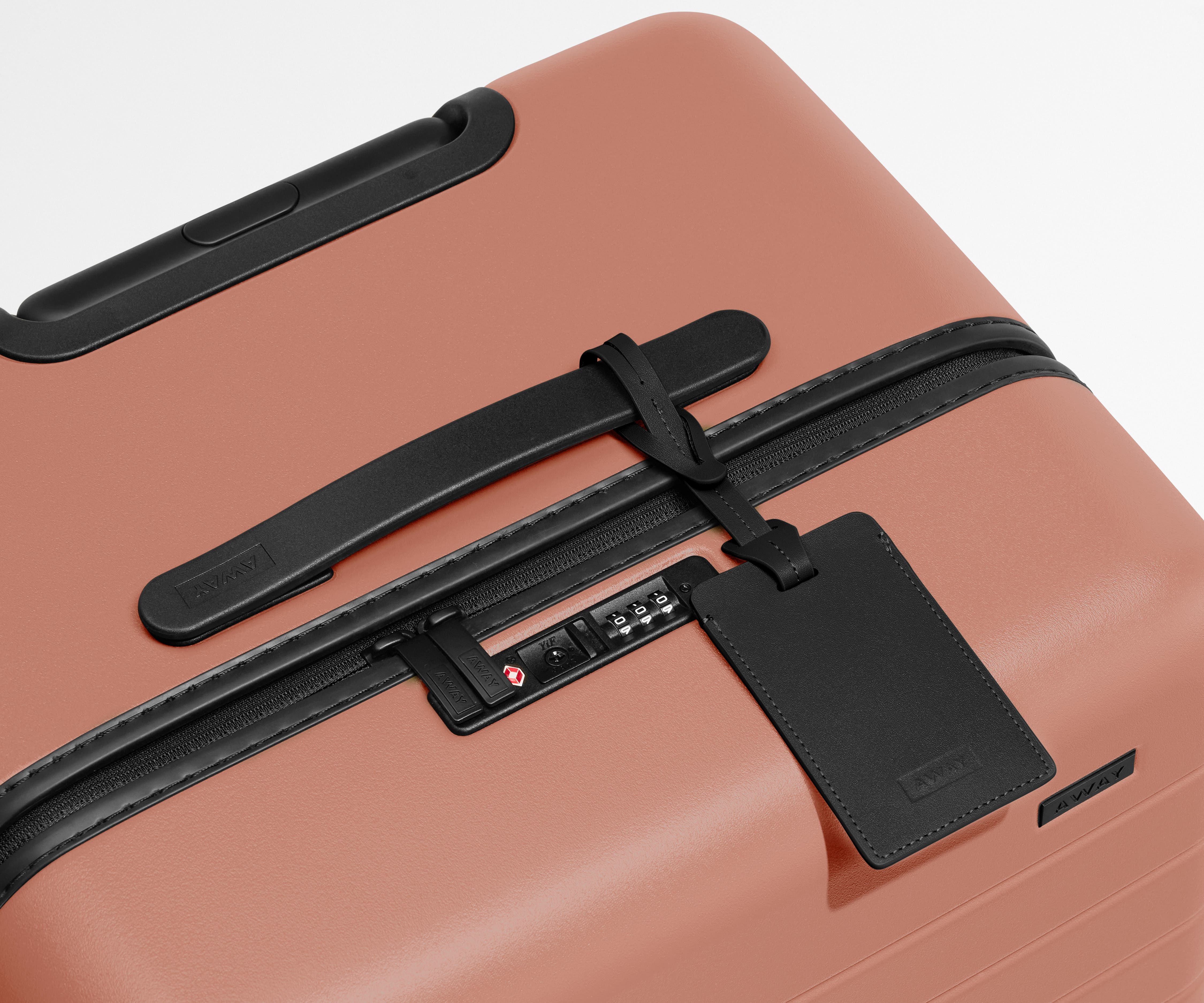 The Trunk suitcase in Clay Pink shown shown from above highlighting TSA-approved combination lock and recycled leather luggage tag