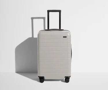 Front product view of The Bigger Carry-On suitcase in Cloud Gray with raised handle