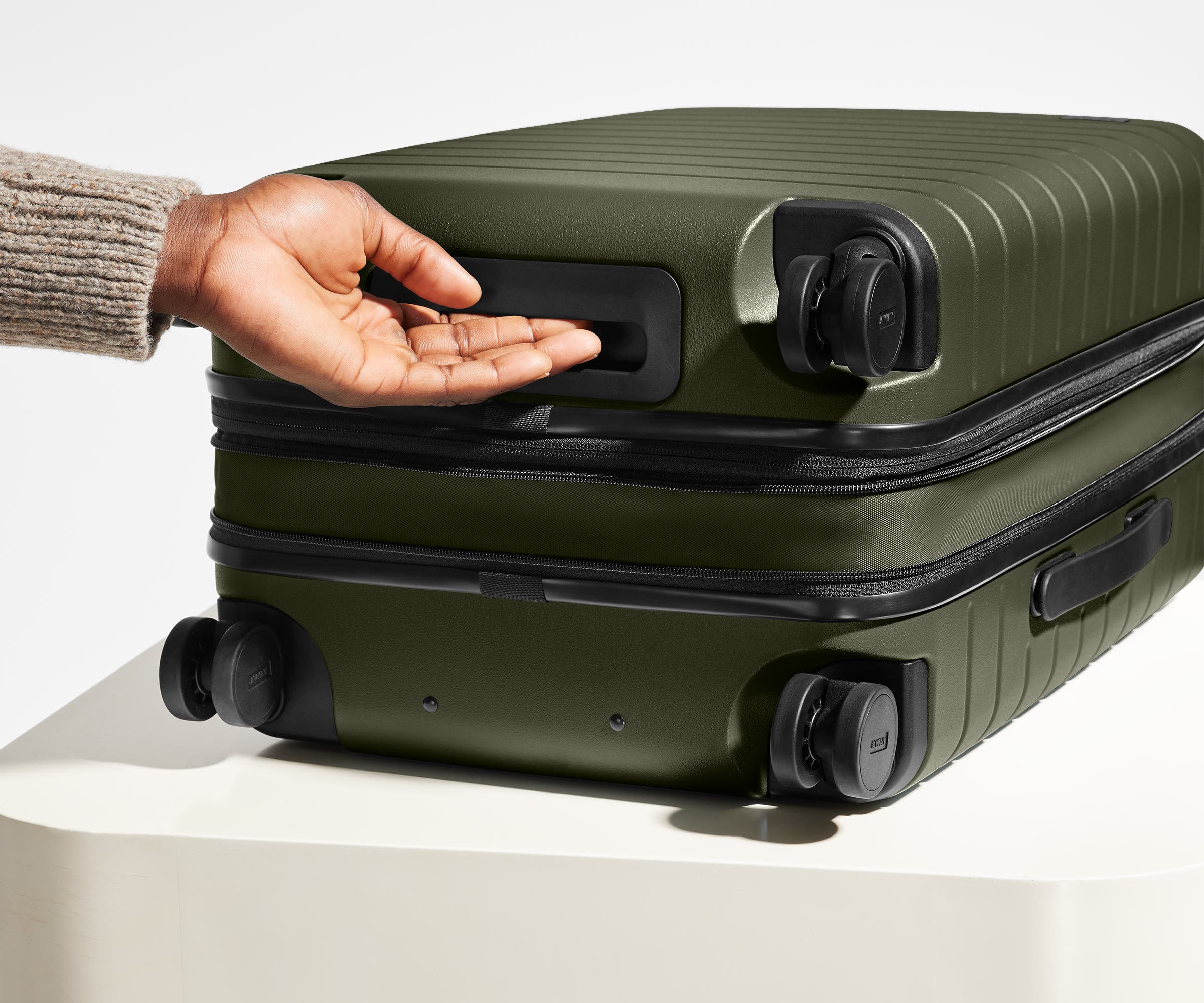 The Carry-On Flex suitcase in Olive Green shown from below highlighting the underside grab handle