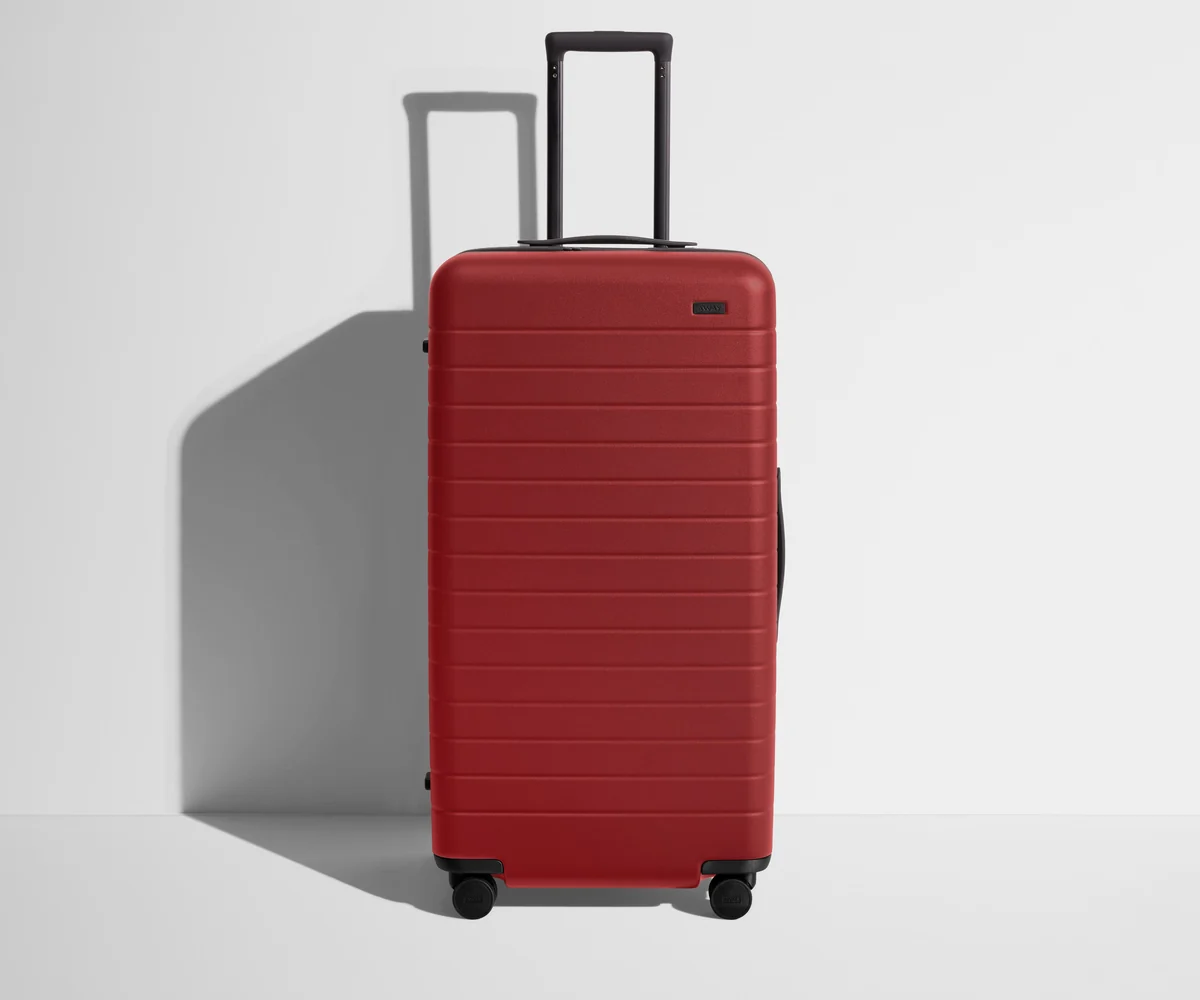 Front product view of The Trunk suitcase in Tango Red with raised handle