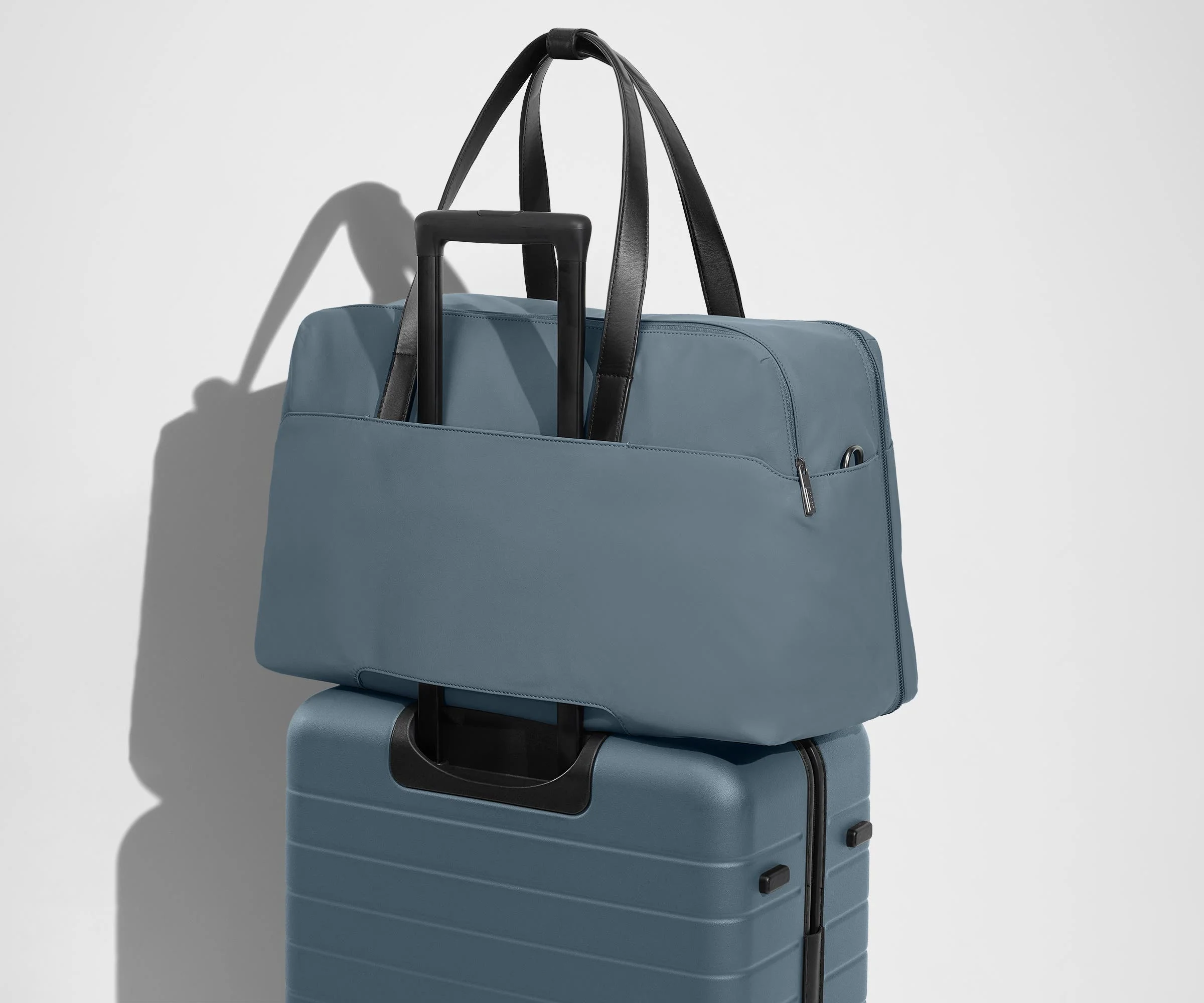 Weekender sitting on an Away Large suitcase, using the trolley sleeve pass-through
